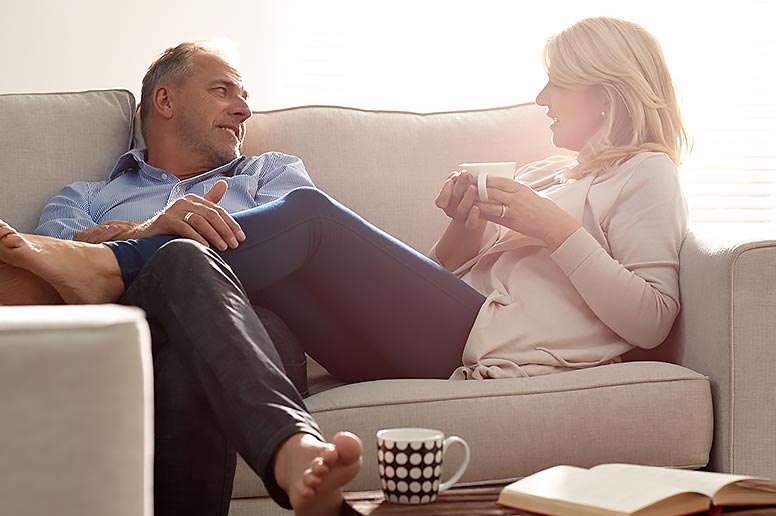 Relaxed couple on couch discussing options for liposuction