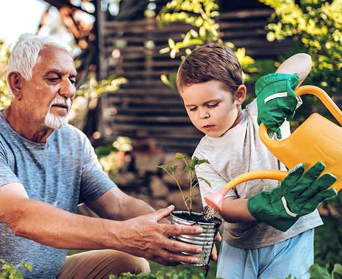 Grandfather and grandson playing in backyard with gardening tools.